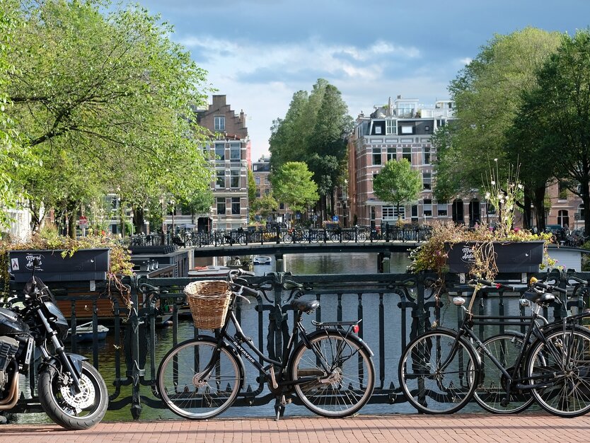 Fahrräder auf einer Brücke in über Amsterdamer Gracht, gutes Wetter, alte Gebäue