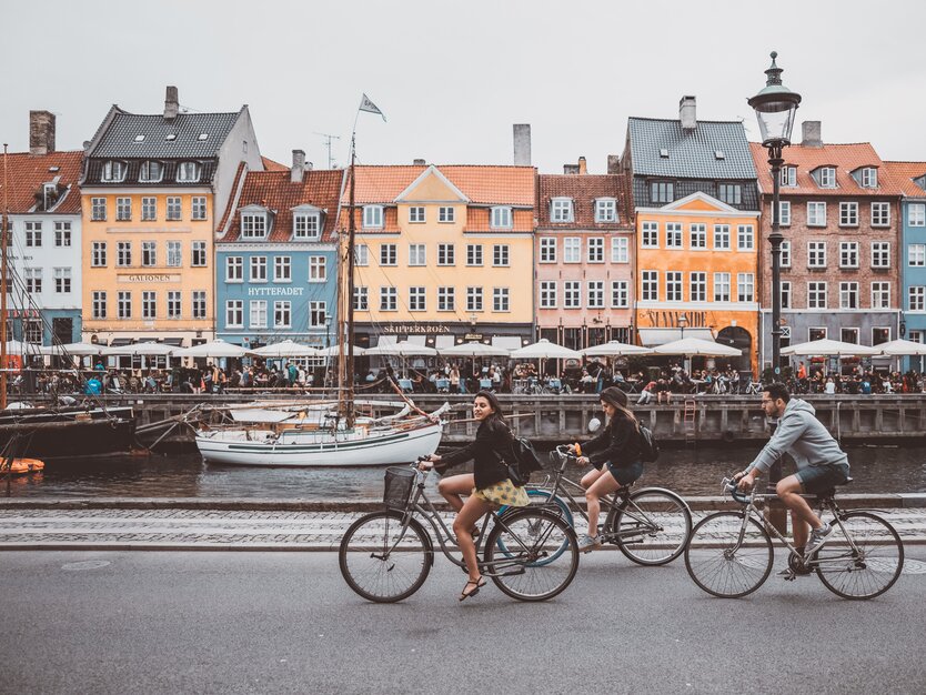 Städtereise Kopenhagen, Stadtrundfahrt, Fahrradfahrer am Hafen, Boote, Wohnhäuser und Restaurants am anderen Ufer