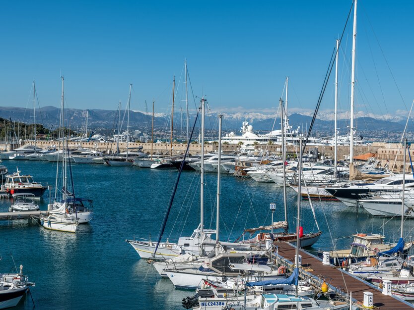 Städtereise Nizza, Frankreich, Ausflug nach Antibes, Blick auf die Boote und Stege im Hafen, Meer, Berge im Hintergrund, blauer Himmel