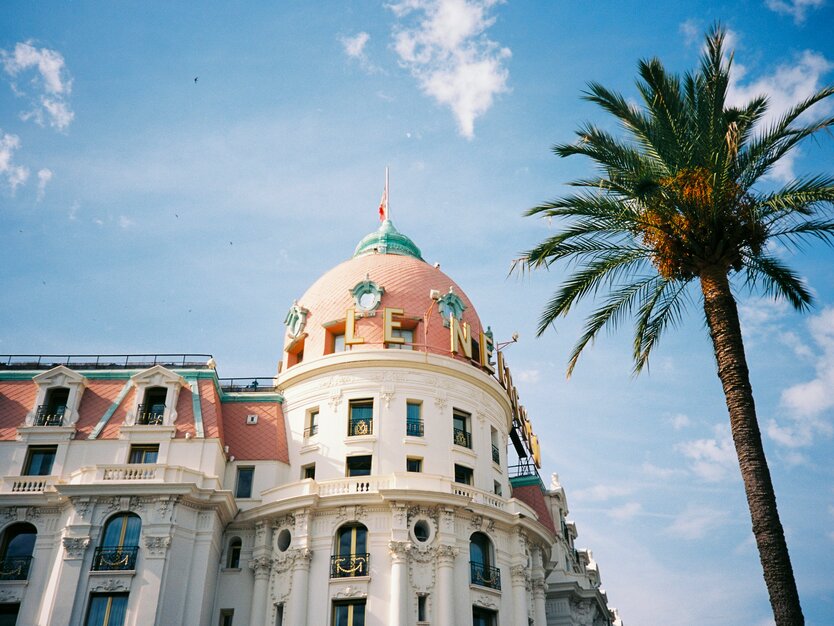 Städtereise Nizza, Frankreich, Stadtrundgang, Außenfassade des Hotels Le Negresco, blauer Himmel, Palmen