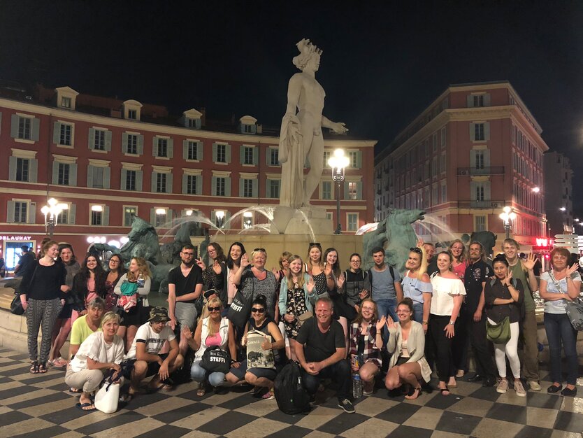 Städtereise Nizza, Frankreich, Szenerundgang, MANGO Tours Reisegruppe Gruppenfoto vor der Fontaine du Soleil bei Nacht