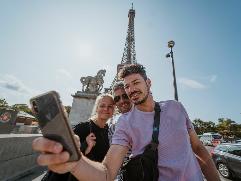 Städtereise Paris, Frankreich, Stadtrundfahrt, Freunde machen ein Selfie vor dem Eiffelturm bei gutem Wetter und Sonnenschein