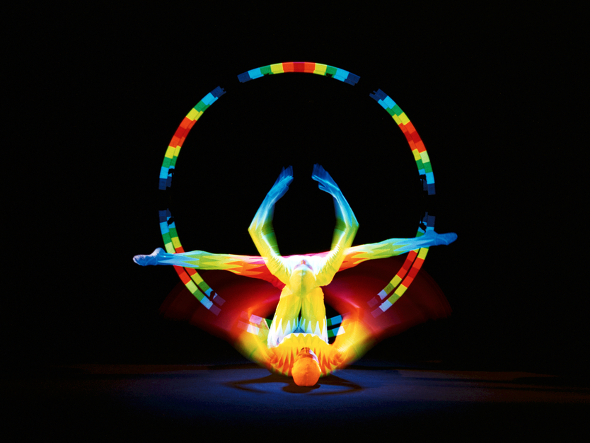 Städtereise Prag, Tschechien, Schwarzlichttheater, bunt beleuchtete Person macht kunstvolle Akrobatik im dunkeln