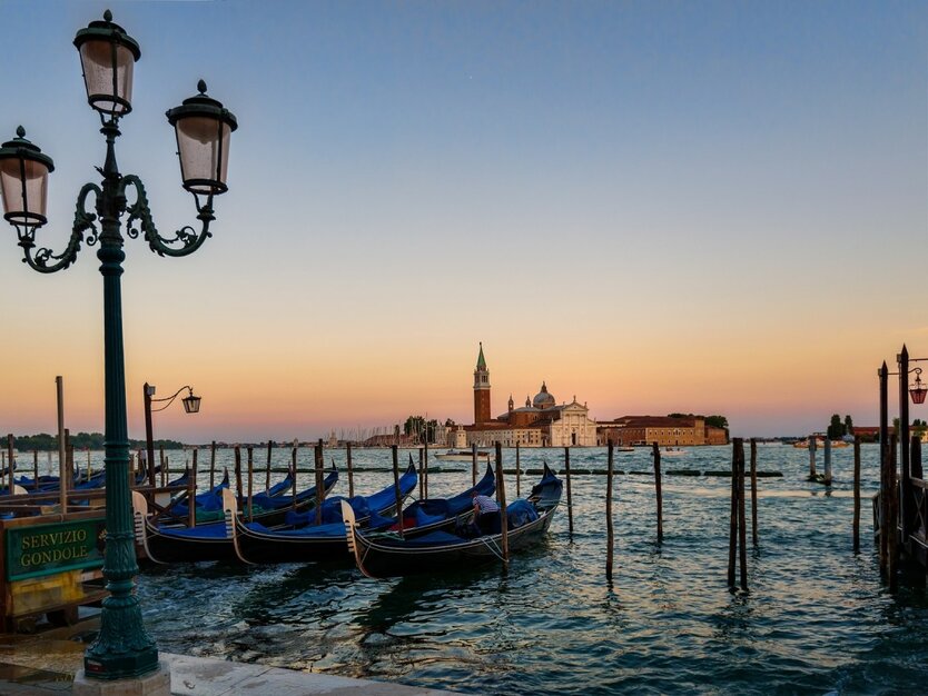 Städtereise Venedig, Italien, Stadtrundgang, Gondeln im Wasser, Markusturm und die Stadt im Hintergrund, Sonnenuntergang, Meer